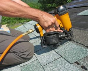 A roofing contractor repairing an asphalt shingle roof.