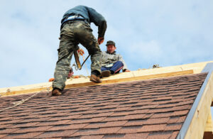 Two technicians installing a new roof.